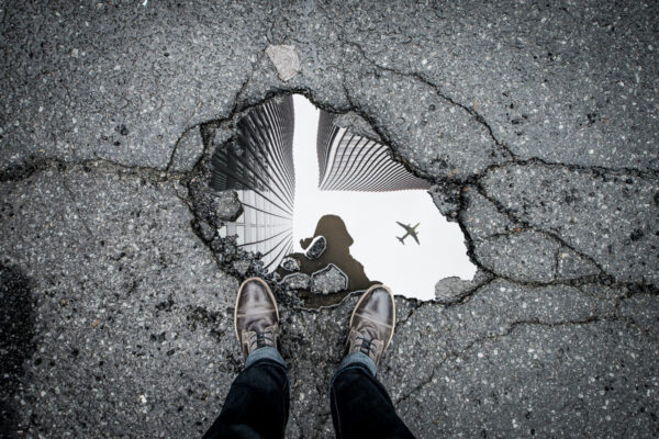 Looking down into a reflection in a puddle of building and an airplane